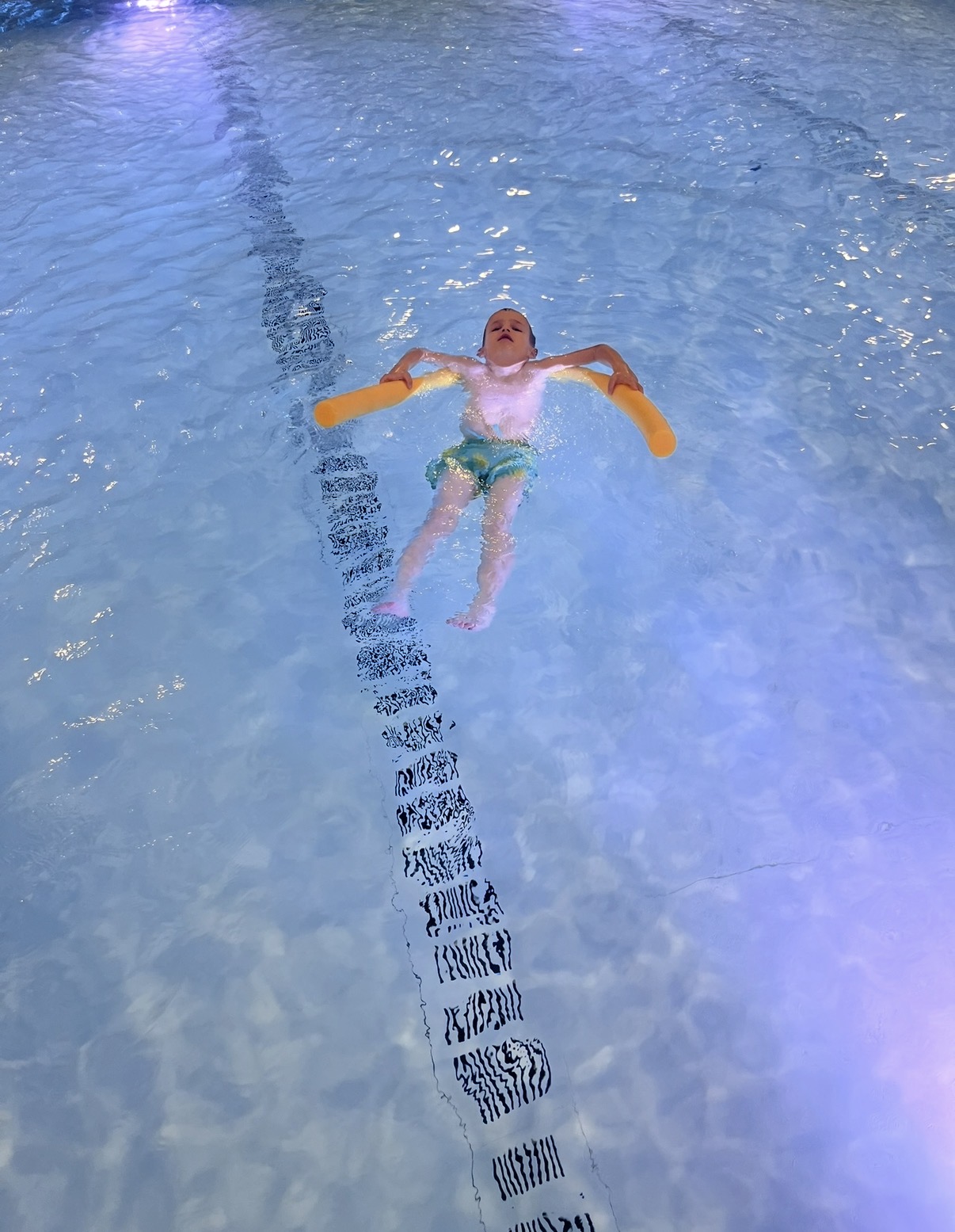 Kind gleitet mit Schwimmhilfe auf dem Rücken.